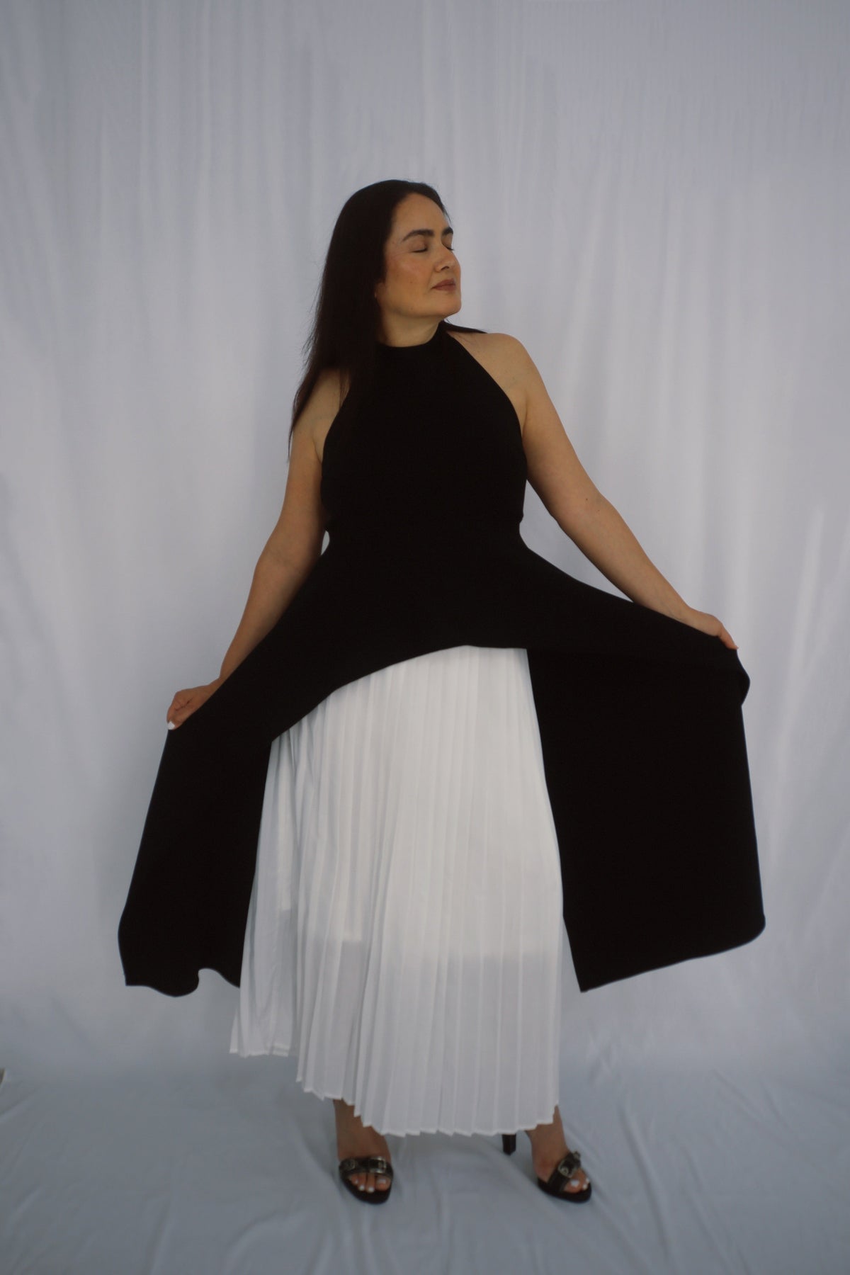 Elegant black halter top with an architectural asymmetrical front hem styled for a clean, modern look.
