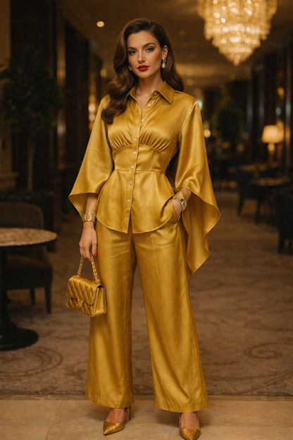 Model wearing an elegant gold satin two-piece outfit with a draped blouse, wide-leg trousers, and pointed heels in a luxury hotel setting.
