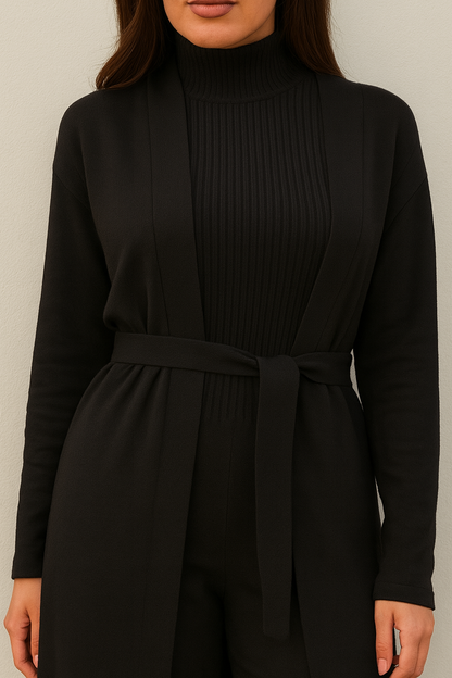 Black ribbed dress with a belt on a plain background