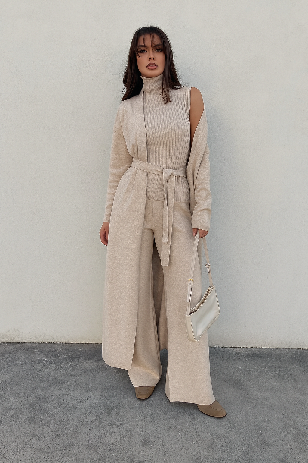 Woman wearing a beige knit outfit with wide-leg pants against a plain background