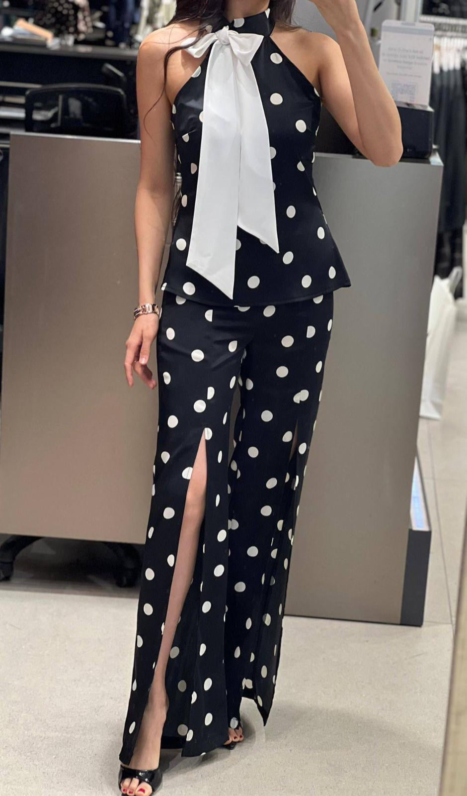 Luxury black and white polka dot matching set with tailored peplum top and high-waisted slit pants, refined evening fashion look for special occasions.