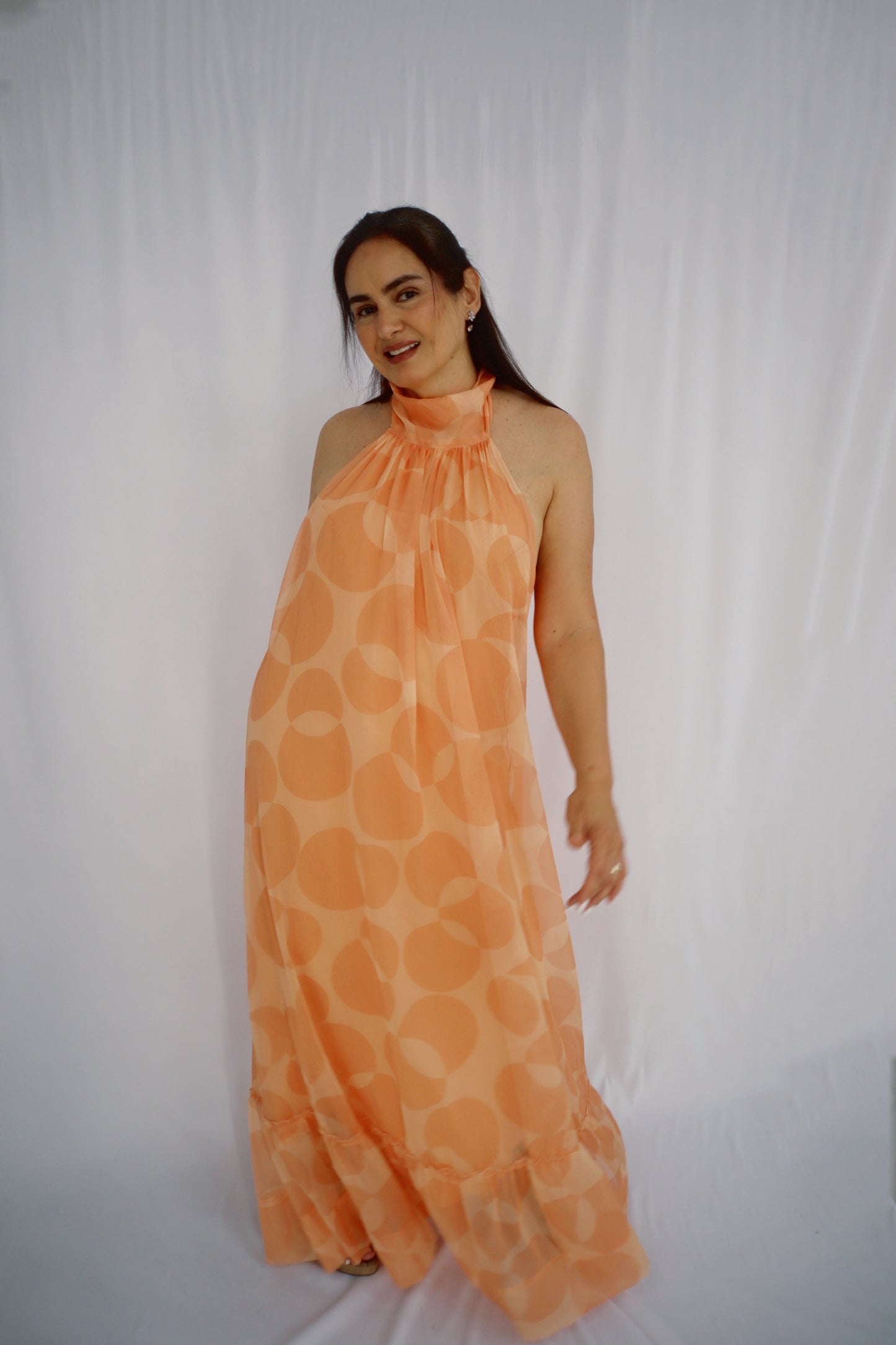 Woman styling a peach halter maxi dress with a ruffle hem, perfect for summer parties and outdoor celebrations