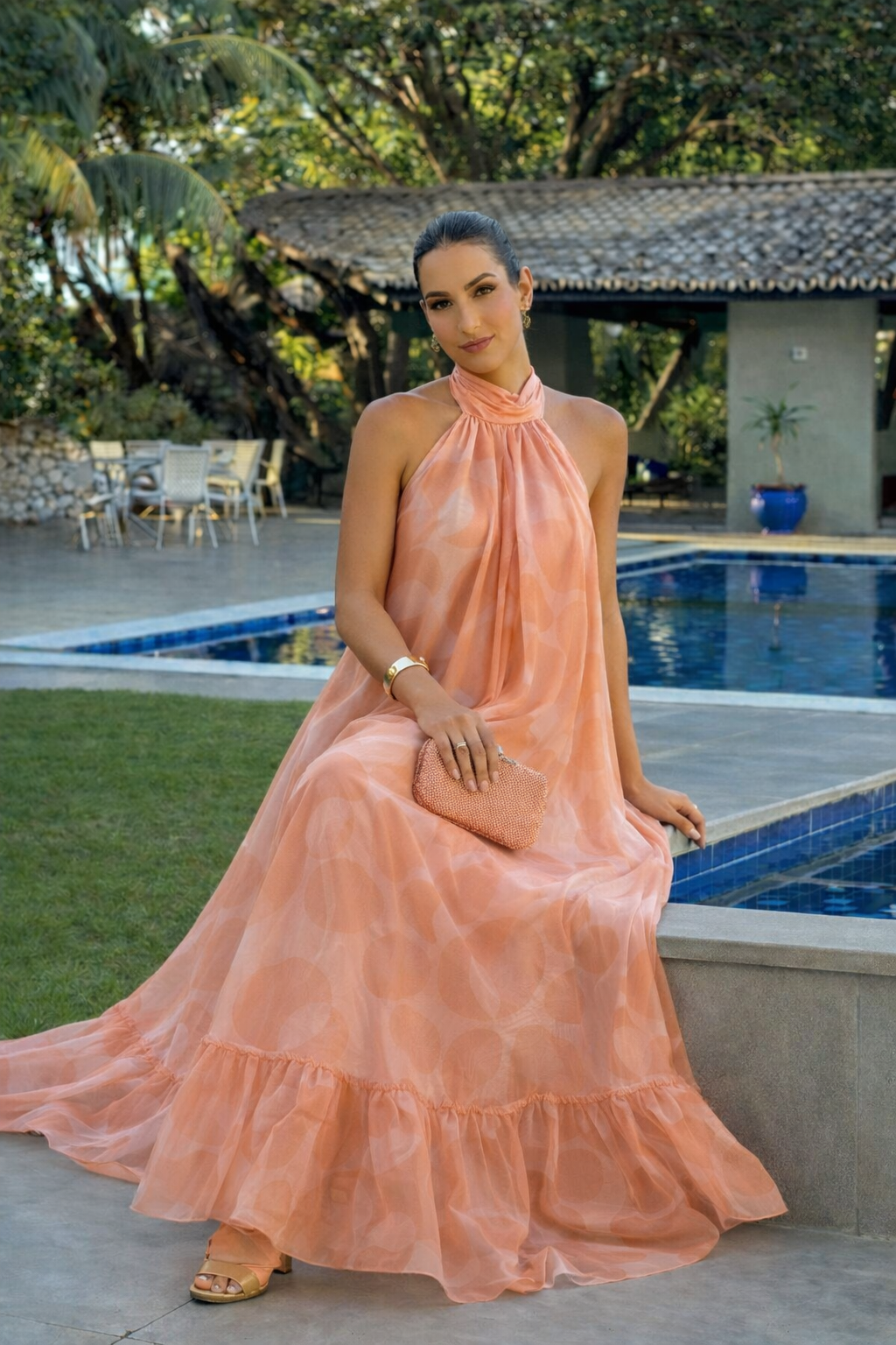 Sleeveless peach halter maxi dress with soft drape and flowing skirt worn by a woman smiling outdoors