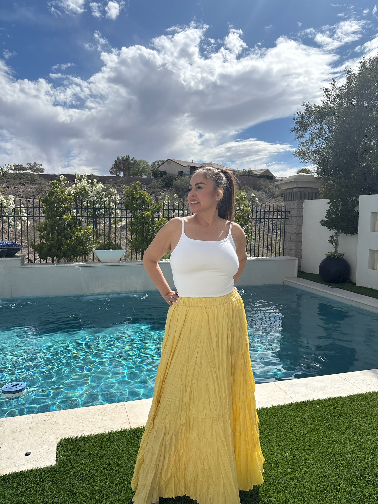 Model wearing The Limoncello Maxi, a flowing butter yellow crinkle maxi skirt paired with a white fitted tank top